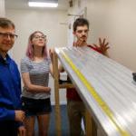Gregory Wietrzykowski, 26岁, 阿莱娜·斯奈德，27岁, 和彼得·谢尔登教授将一辆玩具车推下斜坡，这是他们夏季研究的一部分